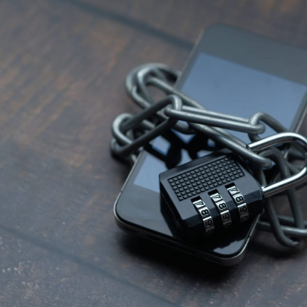 Smartphone secured with a chain and combination lock for cybersecurity protection.